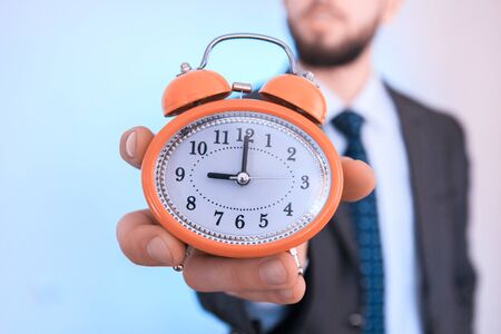 A businessman holding an old alarm clock.の写真素材