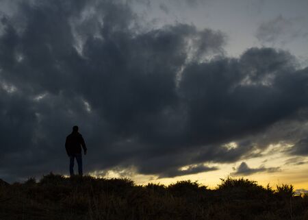 Man standing in a field under grey skyの写真素材