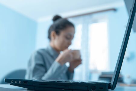 A businesswoman taking a coffee break after working at laptop on deskの写真素材