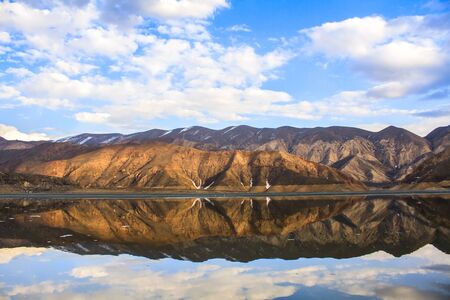 Wonderful landscape with high rocks with illuminated peaks stones in mountain lake reflection. 