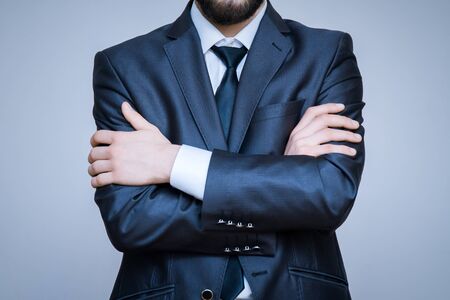 Close-up portrait of elegant male model wearing a suit with arms crossed.の写真素材
