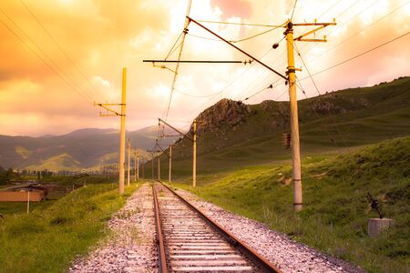 Railway track and power lines at sunset.の写真素材