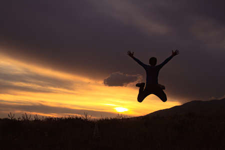Silhouette of a boy jumping at sunset.の写真素材