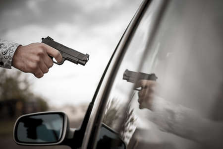 A criminal man pointing gun at the driver.