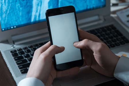 Closeup view of businessman's hands using laptop and mobile phoneの写真素材