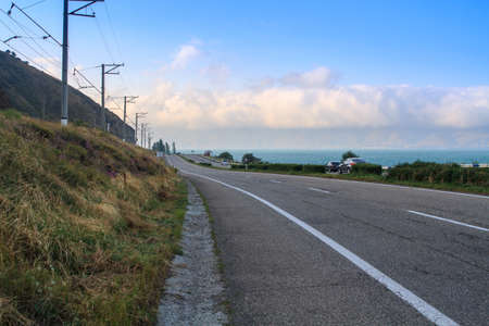 Countryside highway along lake with cloudy sky.の写真素材