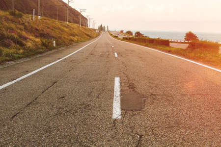 Countryside highway along lake with cloudy sky on sunset.の写真素材