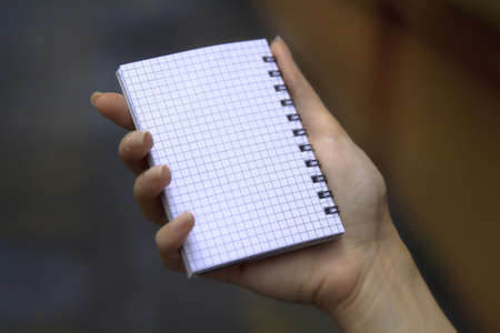 Close up of a woman hand holding a blank notebook.