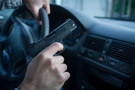 Man in black balaclava with handgun driving a car.の写真素材