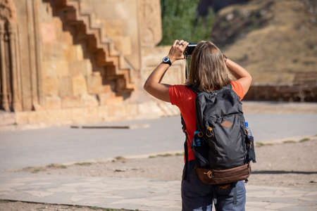 A young tourist girl taking photos of old church.の写真素材