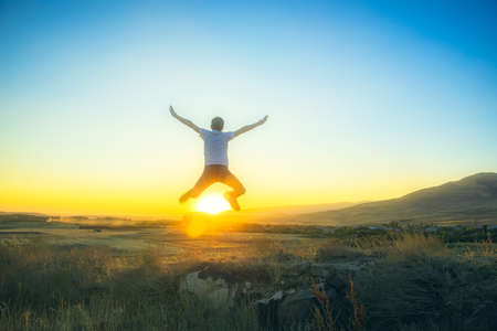 Happy man silhouette jumping with beautiful sunset background.の写真素材