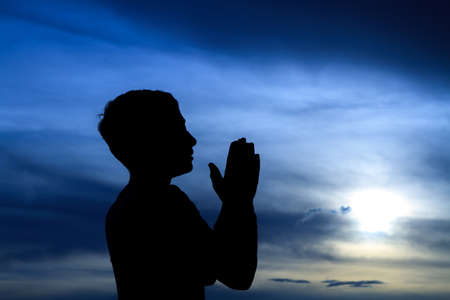 The silhouette of a young boy praying.の写真素材