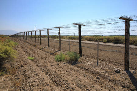Barbed wire fence on blue sky background.