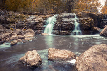 Autumn landscape with mountain river flowing among mossy stones through the colorful forest.の写真素材