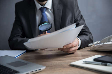 Man hand magnifier with document on desk