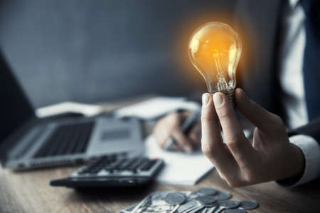 Man hand light bulb on office deskの写真素材