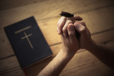 Man hand cross with Bible on wooden backgroundの写真素材