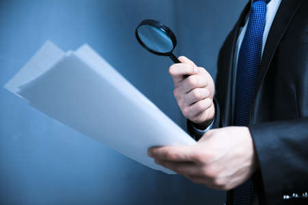 Man hand magnifier and document on dark backgroundの写真素材