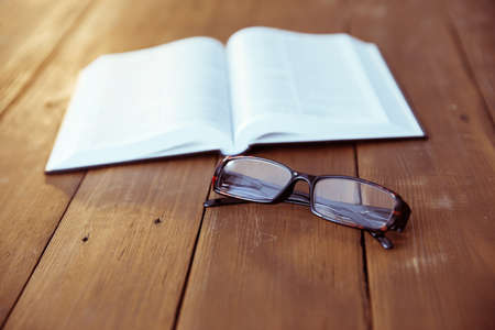 book with glasses on the wooden tableの写真素材