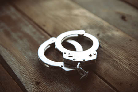 handcuffs on wooden table backgroundの写真素材