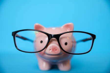 Glasses with piggy bank on blue backgroundの写真素材