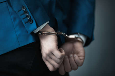 man hand handcuffs on dark backgroundの写真素材