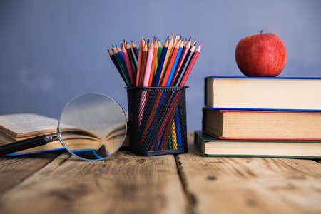 books with pencils and apple on table