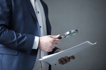 man hand holding magnifier and documentの写真素材