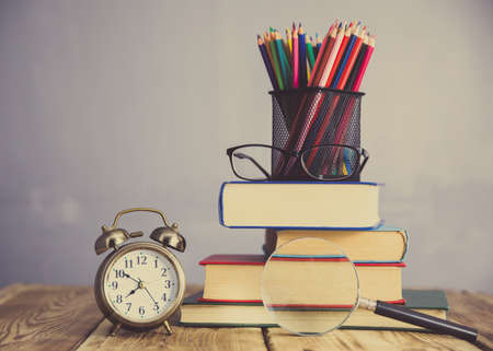 colorful pencils on book with clock on table