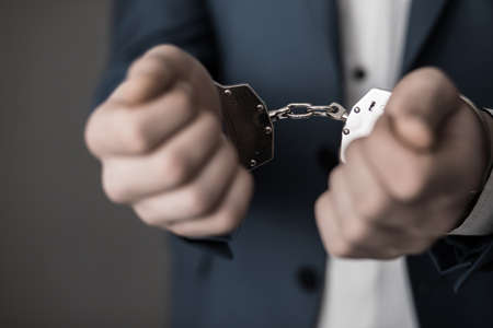 businessman hand handcuffs on dark backgroundの写真素材