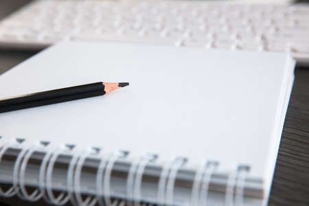 pencil on notepad with keyboardの写真素材