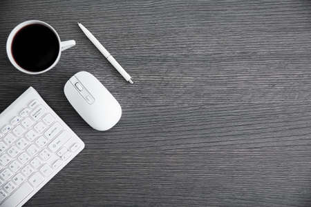 computer keyboard with cup of coffee on tableの写真素材