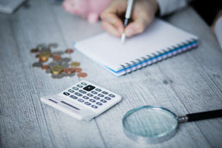 man hand notepad with coins on tableの写真素材