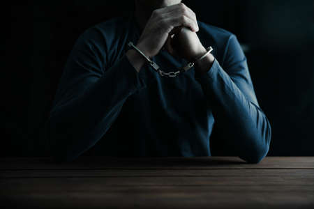 man hand handcuffs on tableの写真素材