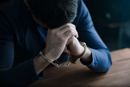 sad man hand handcuffs on tableの写真素材