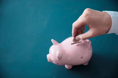 a man hand coin with piggy bank on deskの写真素材