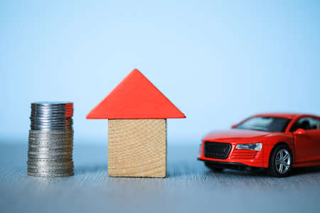 coins with car and house model on deskの写真素材