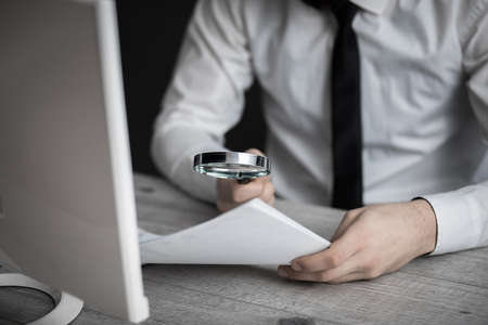 man hand magnifier on document in office desk