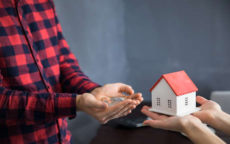 woman hand house model with man hand holding coins