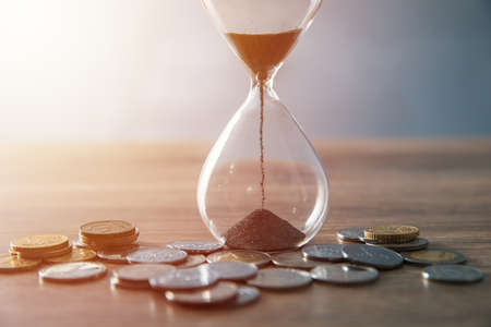hourglass with coins on table