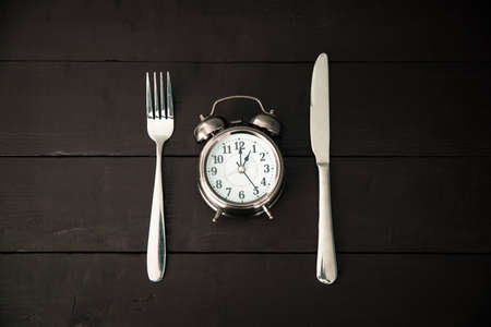 Alarm clock with fork and knife on the tableの写真素材