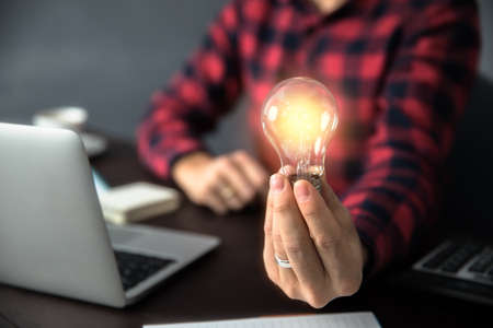 man hand light bulb on working deskの写真素材