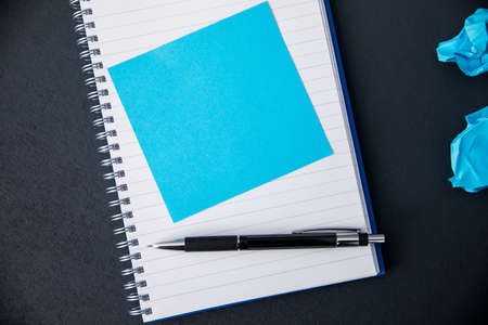 blue paper on notepad on black desk