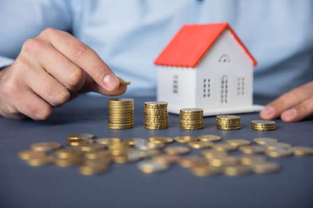 man hand coins with house model on deskの写真素材