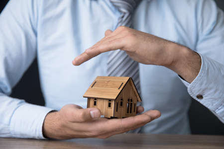 man hand holding house model on desk