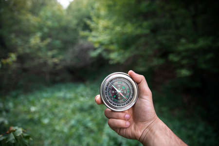 man hand compass in green forest