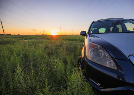 car parked in a field at the sunsetの写真素材