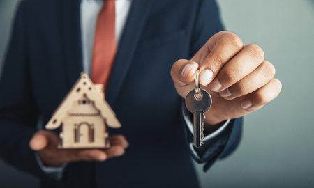 man hand holding key with house modelの写真素材