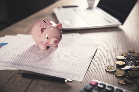 piggy bank on document with coins on deskの写真素材