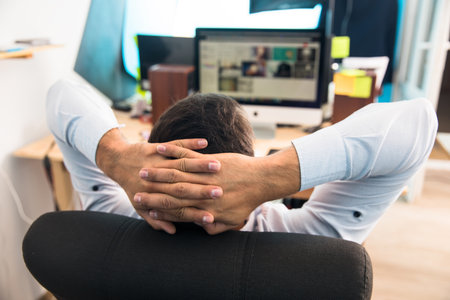 man holding hand on the back of the head and working at the desk